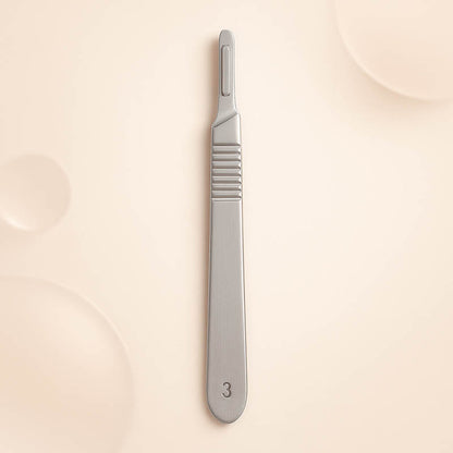 Luxury #3 stainless steel dermaplaning handle displayed on a soft blush background — engraved with “3” near the base, featuring a polished, ergonomic design ideal for estheticians and professional skincare treatments, styled for high-end Shopify product listings.