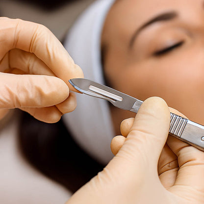 Professional esthetician attaching a #10 dermaplaning blade to a stainless steel handle using proper technique — showcasing safety, precision, and professional skincare preparation in a clean, spa-like treatment environment.