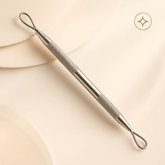 Luxury stainless steel comedone extractor tool displayed on a soft blush background — dual-ended design with loop and lancet tips for safe, precise blackhead and whitehead removal, styled in a high-end spa aesthetic for professional estheticians and skincare specialists.