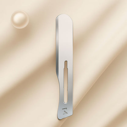 Close-up of a polished stainless steel number 14 dermaplaning blade used by estheticians for precision exfoliation treatments, displayed on a soft neutral background for a luxury skincare aesthetic
