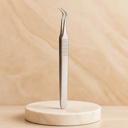 Professional stainless steel pimple popper and blackhead tweezers displayed on a soft beige marble surface with luxury spa lighting, high-end skincare tool for estheticians