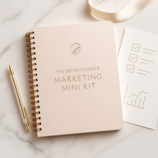 Luxury beauty-industry workbook mockup for estheticians, spiral notebook with gold accents on marble surface.
